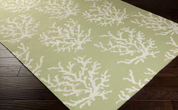 Close-up of the Indio Area Rug. Light green wool rug with a white coral branch pattern. Coastal style. Corner