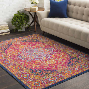 Living room scene with a colorful Inverkeithing Area Rug in burgundy, orange, and navy, styled with a beige sofa and wood accents. Roomscene-Rectangle