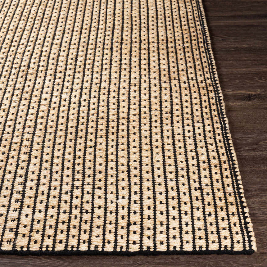 Close-up of Iqaluit Natural Jute Rug showing black stitched lines and beige jute texture on a dark wood floor. Front