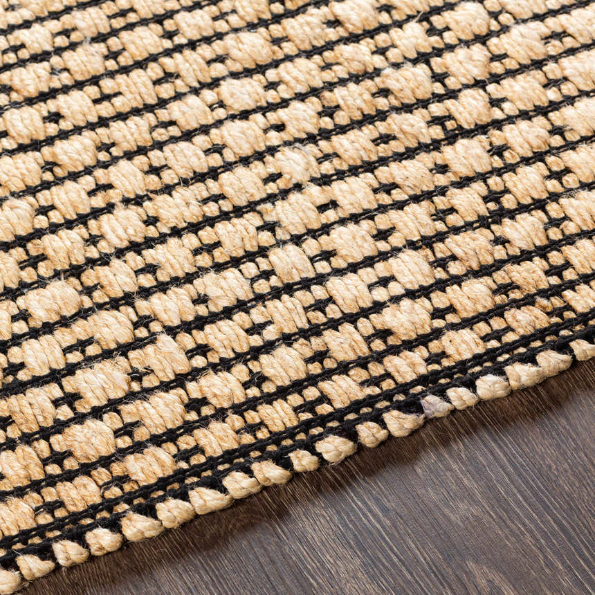 Close-up of Iqaluit Natural Jute Rug showing beige jute and black woven design and texture on dark wood floor. Texture