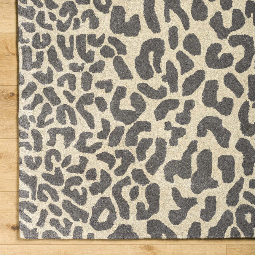 Close-up of the Iseul Leopard Print Area Rug, a hand-tufted wool rug with a dark gray leopard pattern on a taupe background. Corner