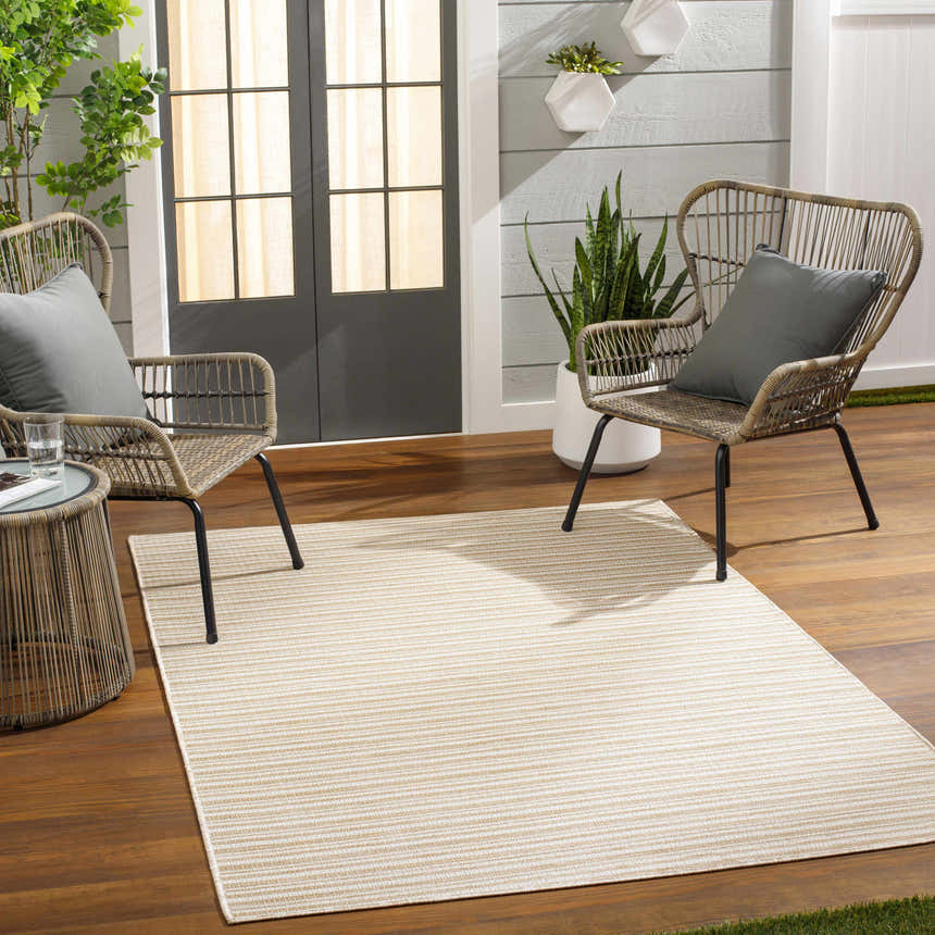 Outdoor patio scene with Greg Beige Area Rug, wicker chairs, gray cushions, and wood flooring. Roomscene-Rectangle