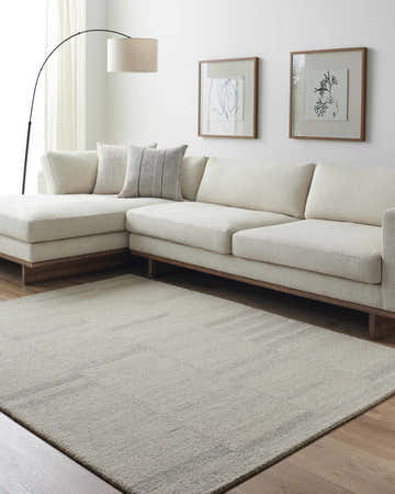 Living room scene with beige Jaina Modern Wool Rug, sectional sofa, and minimalist art. Roomscene-Rectangle