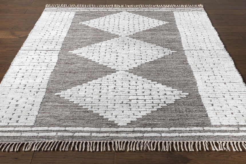 Close-up of the Junction Carpet - Clearance. Brown and light beige wool rug with a geometric diamond pattern and fringe. Front