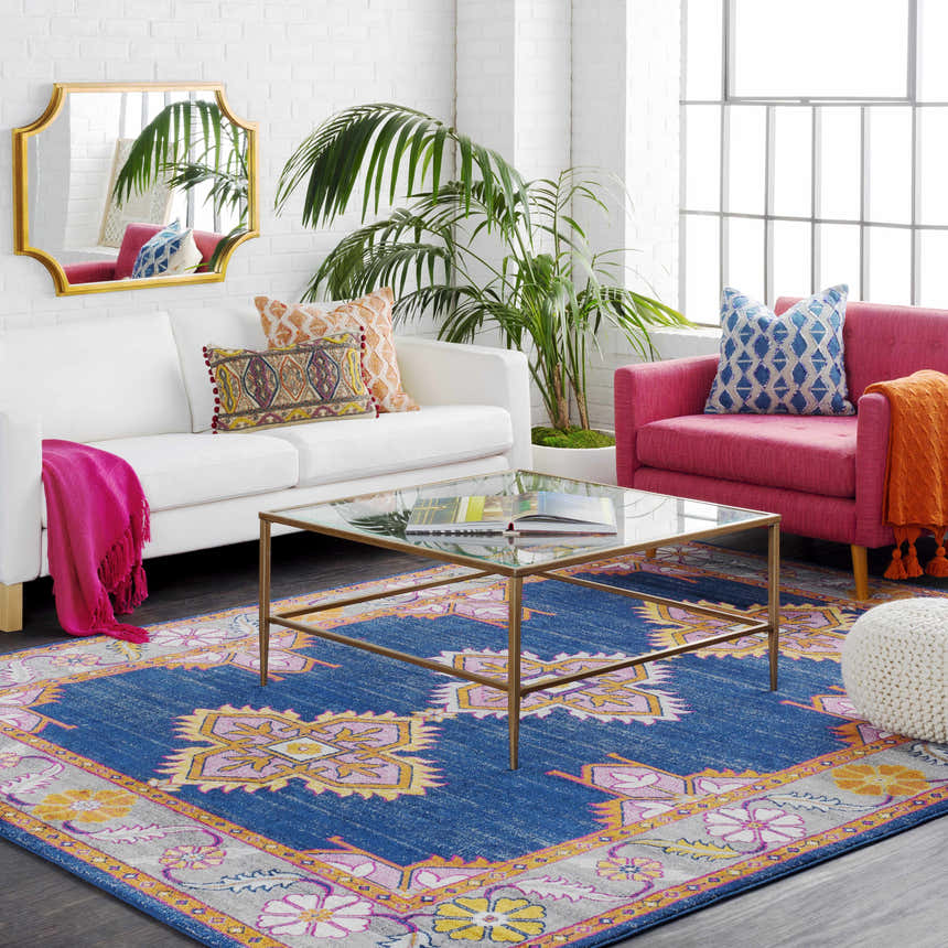 Living room scene with a Kaitlyn Navy Area Rug, white sofa, pink chair, and glass coffee table. Roomscene-Rectangle