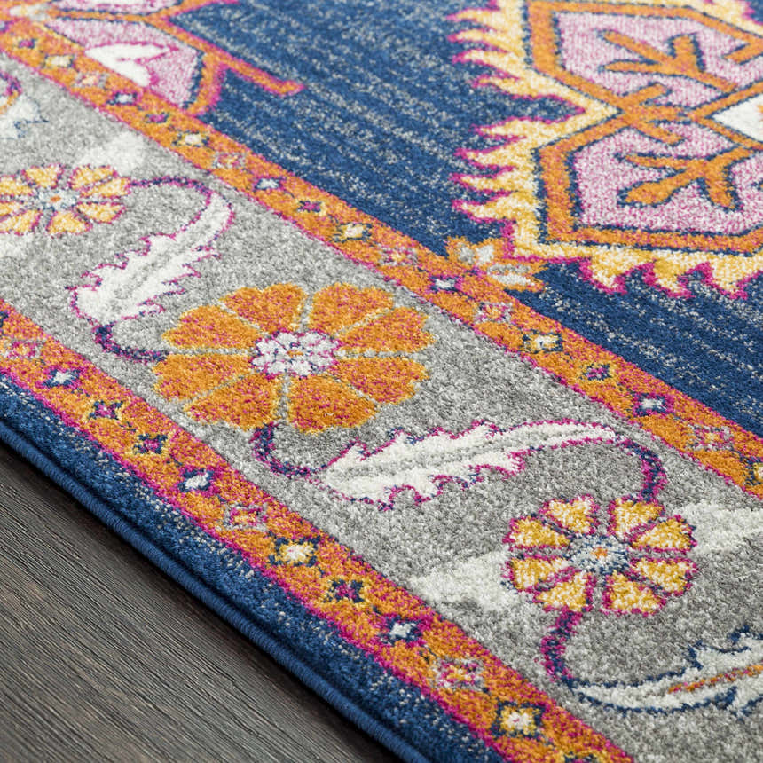 Close-up of the Kaitlyn Navy Area Rug showing its bohemian floral pattern and colors: navy, orange, gray, pink. Texture