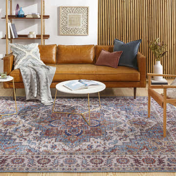 Living room scene with a Kapaa Traditional Area Rug, brown leather sofa, and wood accents. The rug features blue and orange tones. Roomscene-Rectangle