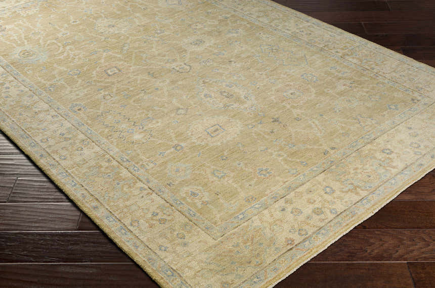 Close-up of the Karalee Handmade Wool Area Rug showcasing its beige, light olive, and dusty pink traditional pattern. Corner