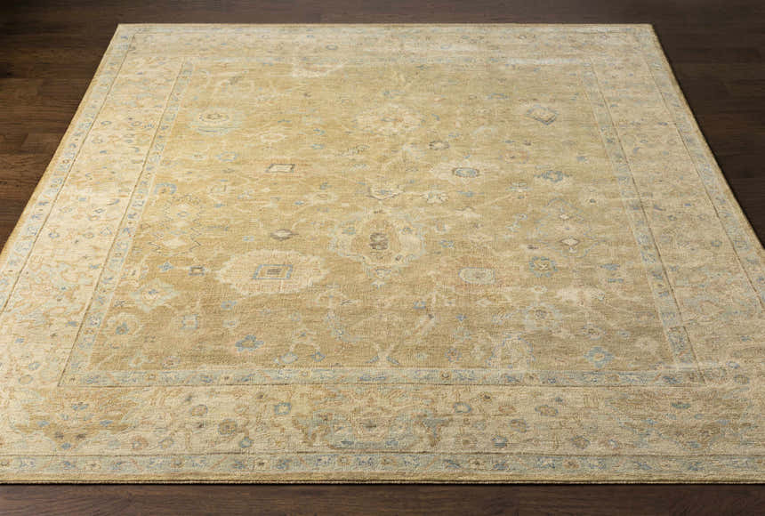 Handmade Karalee Wool Area Rug in beige, brown, pink, olive, seafoam, slate, and yellow on a dark wood floor. Front