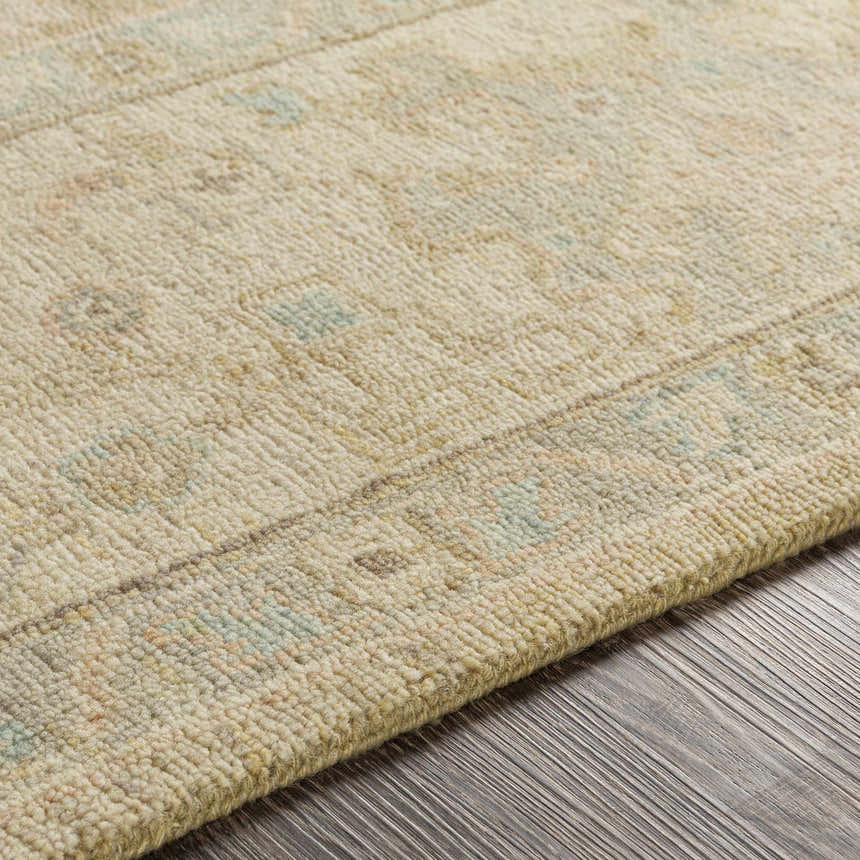 Close-up of the Karalee Handmade Wool Area Rug showing beige, dusty pink, and light olive colors. Hand-knotted texture detail. Texture