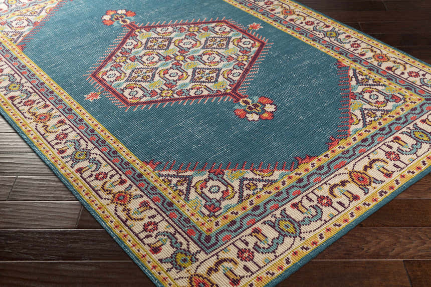 Close-up of the Kaser Carpet on dark wood floor. Features a teal field and traditional floral border. Corner