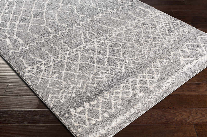 Close up of the Kessingland Area Rug, a gray rug with a white geometric pattern. Corner