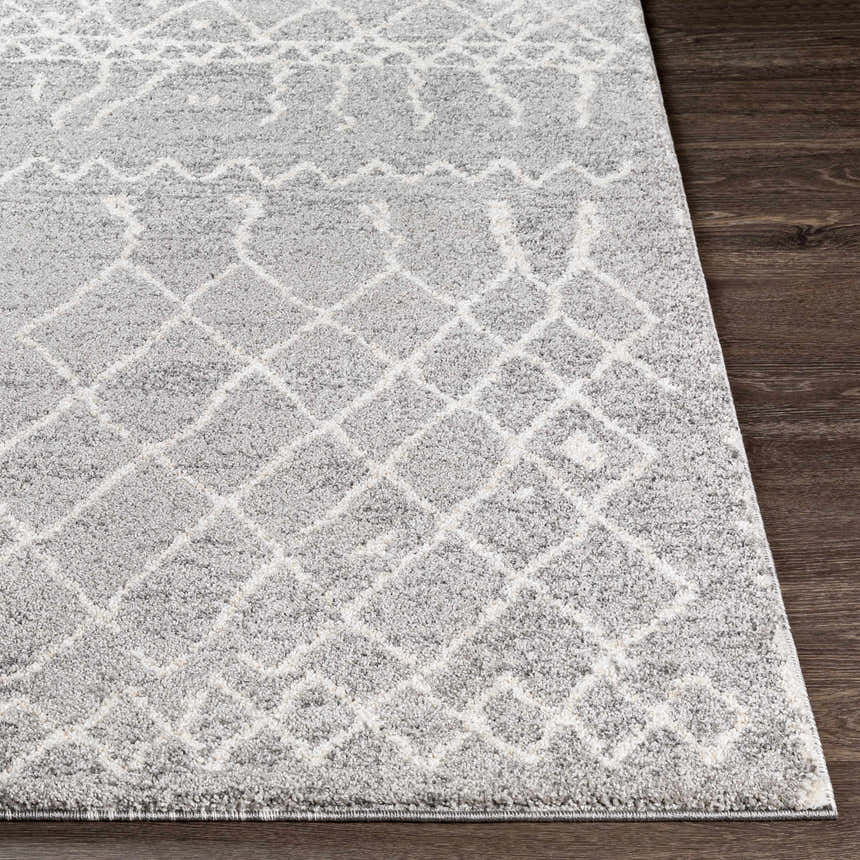 Close-up of the Kessingland Area Rug, showing its gray and off-white geometric pattern and textured weave on a dark wood floor. Front