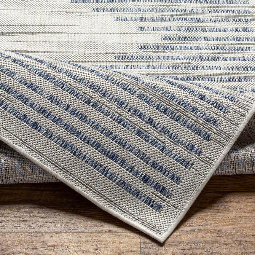 Close-up of the Khandallah Area Rug showing a geometric pattern in cream and navy. Machine woven texture detail. Fold