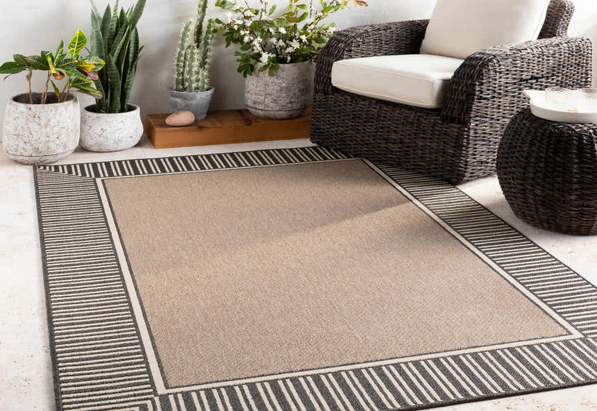 Styled patio with beige Kidron Area Rug, brown wicker chair and side table, potted plants, and neutral tones. Roomscene-Rectangle