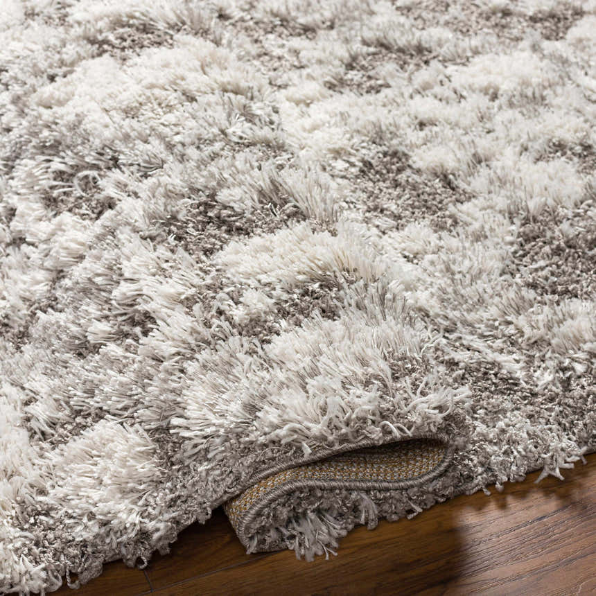 Close-up of the plush texture and gray and off-white colors of the Kilgetty Gray Cloudy Shag Rug. Fold