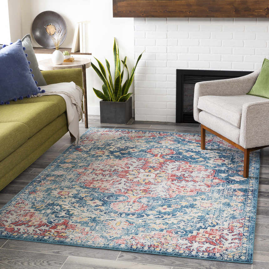 Living room scene with blue, red, and saffron Knowsley Area Rug, green sofa, and white brick fireplace. Roomscene-Rectangle