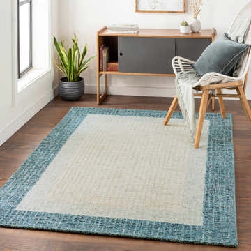 Living room scene with a cream and teal Kuruman Area Rug, white chair, and modern wood cabinet. Roomscene-Rectangle