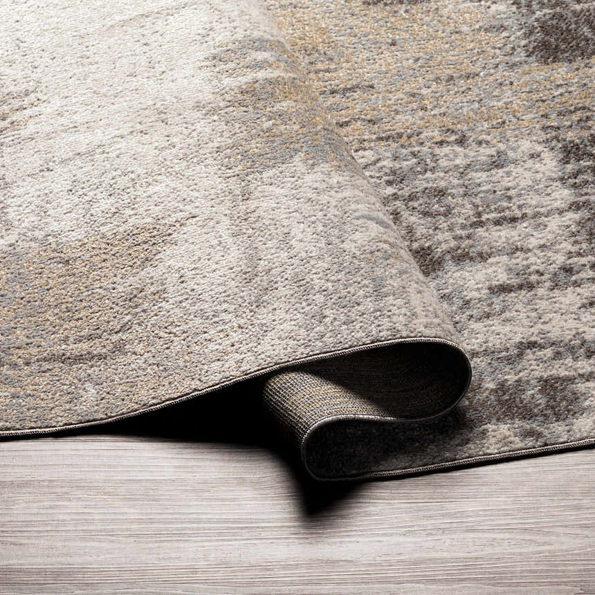 Close-up of the Kuyucak Washable Area Rug showing its brown, cream, and gray abstract design and soft, textured weave. Fold