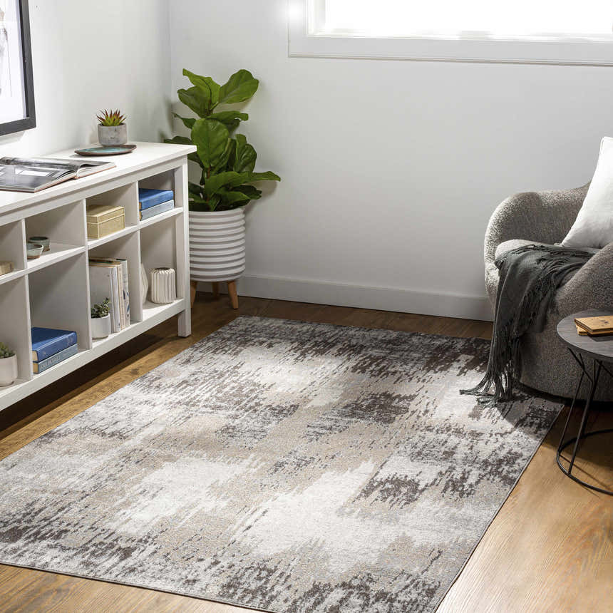 Living room scene with a brown, cream, and gray Kuyucak Washable Area Rug. Modern decor with white shelving and gray armchair. Roomscene-Rectangle