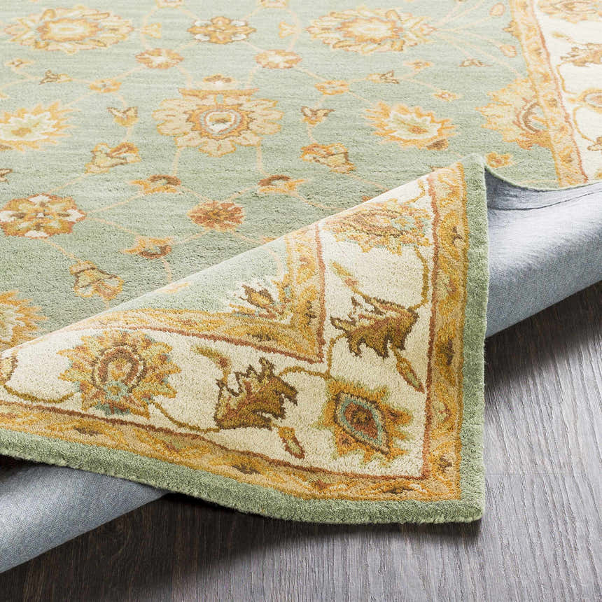 Close-up of the Lagrange Sage Regency Wool Carpet showing sage, beige, and brown floral pattern and hand-tufted texture. Fold