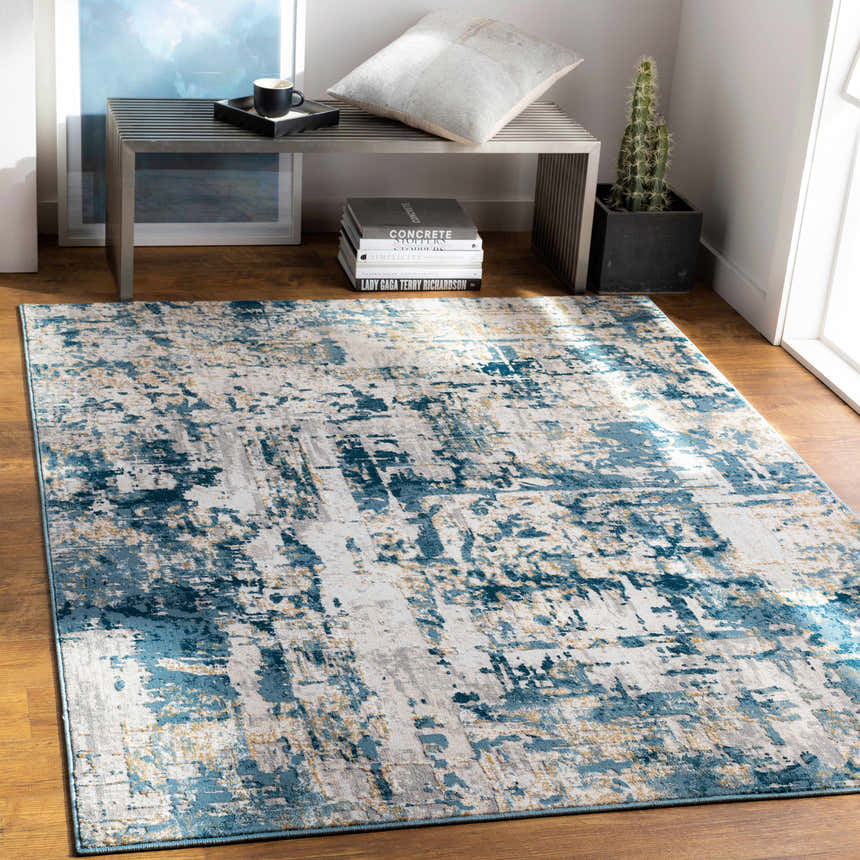 Living room scene with a Larne Area Rug in blue, gray, and beige, styled with a metal bench and wood floors. Roomscene-Rectangle
