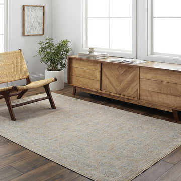 Living room scene with a Coby Cream Avant Garde rug, wood floors, mid-century cabinet, woven chair, and natural light. Roomscene-Rectangle