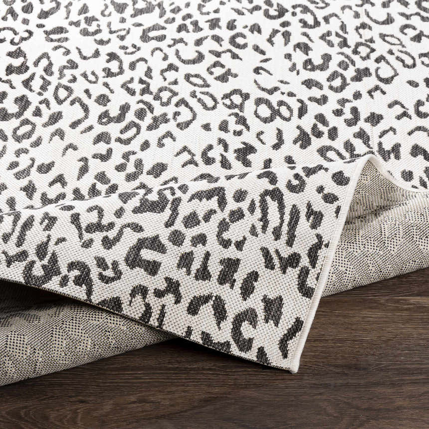 Close-up of the Alderbury White Leopard Print Rug showing its black and off-white animal print design and woven texture. Fold