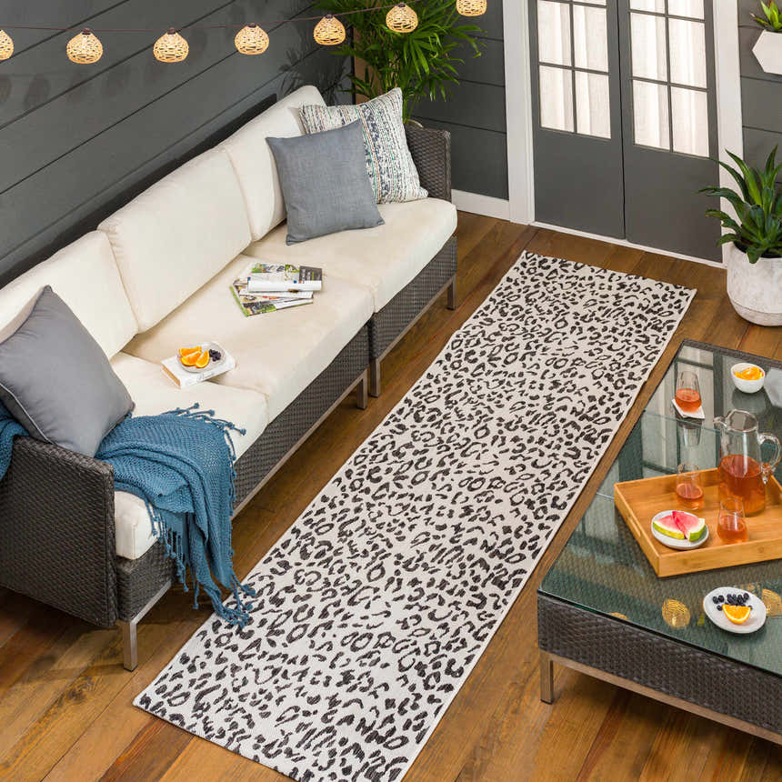 Outdoor patio scene with a white couch and Alderbury White Leopard Print Rug runner on a wood deck. Roomscene-Runner
