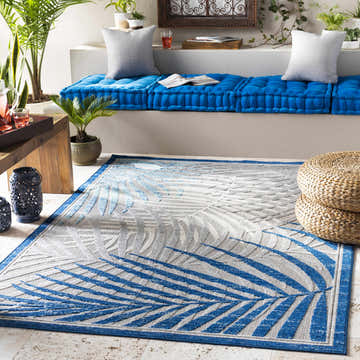 Coastal patio scene with blue cushions, woven ottomans, and Boutique Rugs Liberal Area Rug with blue and gray palm leaf design. Roomscene-Rectangle