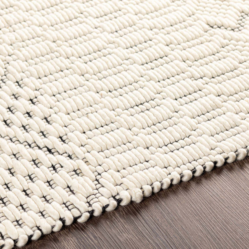 Close-up of the hand woven Limoges Area Carpet. Cream wool rug with subtle black geometric pattern and chunky texture. Texture