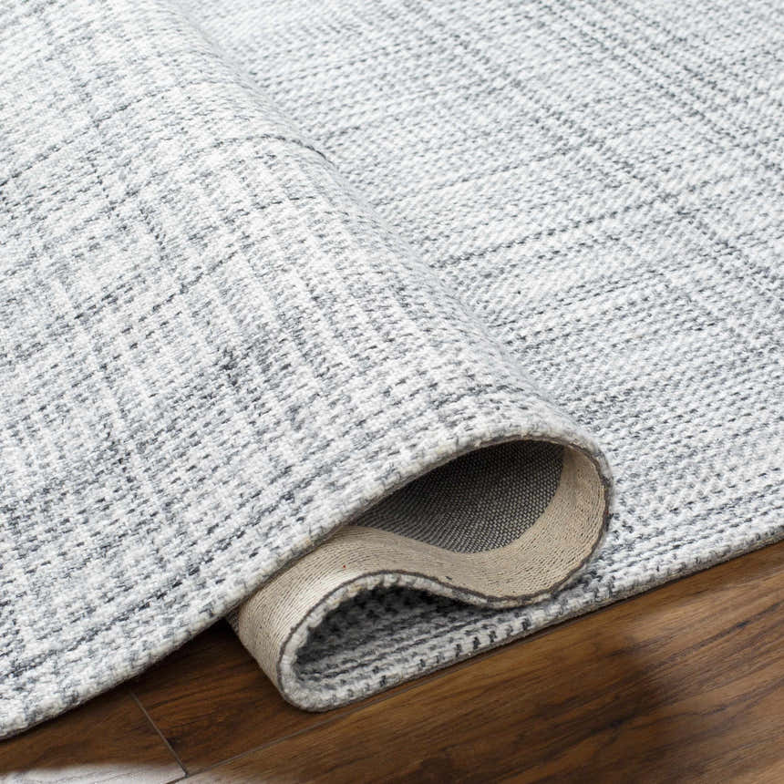 Close-up of the hand-woven Lubna Light Slate Area Rug showing texture and pattern details in black, charcoal, and light slate. Fold