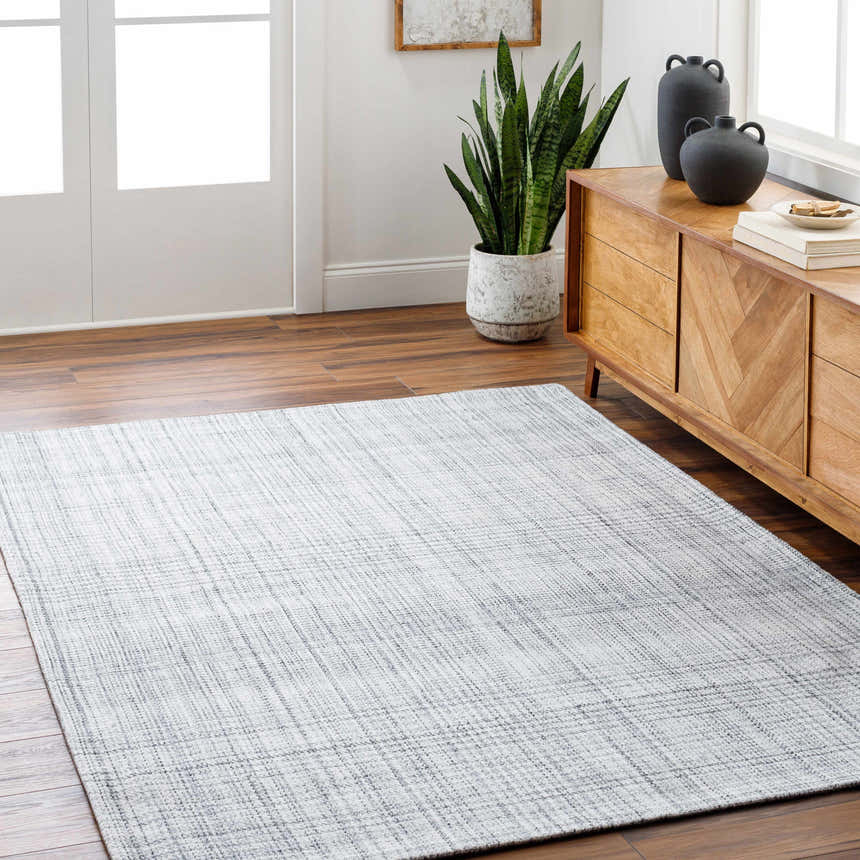 Living room scene with a light slate Lubna Area Rug, wood floors, and a mid-century modern cabinet. Roomscene-Rectangle