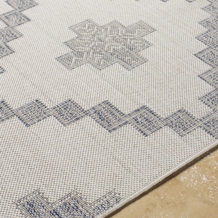 Close-up of the Lanigan Indoor Outdoor Rug showing the off-white base and blue Southwestern-inspired geometric pattern. Texture