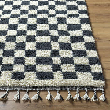 Close-up of the hand-woven Uttam Area Rug. Black and light silver wool rug with a checkerboard pattern and tasseled fringe. Front