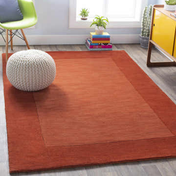 Living room scene with a Bordered Solid Brick Red Wool Rug, white pouf, green chair, and yellow cabinet. Roomscene-Rectangle