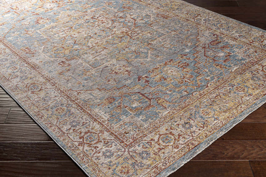 Close-up of the Lumpkin Area Rug, featuring a traditional pattern in brick red, charcoal, light beige, and pale blue. Corner