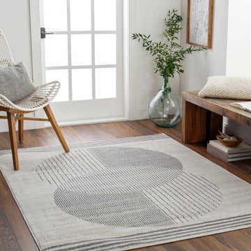 Entryway with Elvi Area Rug in dark gray and natural gray, featuring a geometric pattern, styled with a white chair and wooden bench. Roomscene-Rectangle