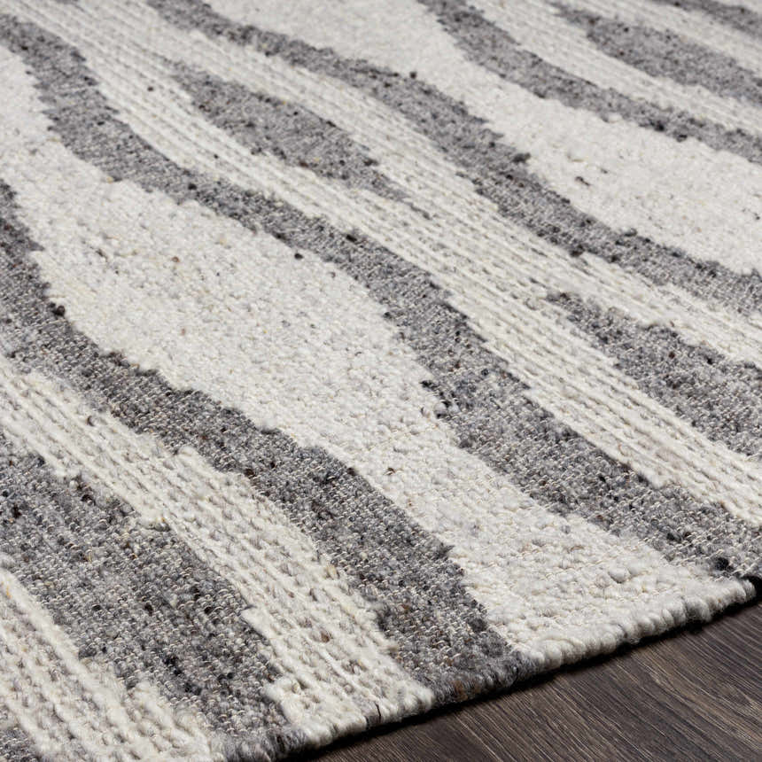 Close-up of Lavalwaves Hand Woven Wool Carpet showing flatweave texture and brown, charcoal, cream, and gray colors. Texture