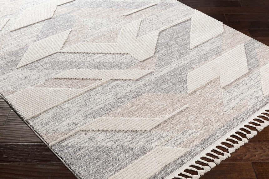 Close-up of the Magazine Geometric High/Low Pile Rug. Gray, tan rug with raised geometric pattern and tassels. Corner
