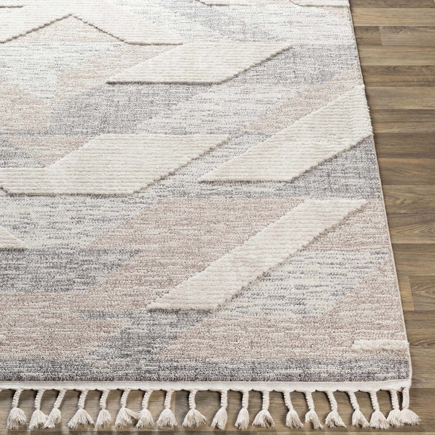 Close-up of Magazine Geometric High/Low Pile Rug with Tassels. Gray, tan rug features a geometric pattern and tassel fringe. Front