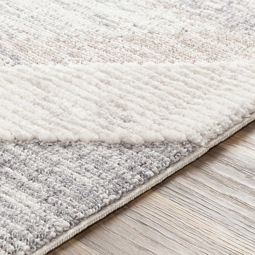 Close-up of the Magazine Geometric High/Low Pile Rug. Gray and tan rug with a geometric design and textured surface. Texture