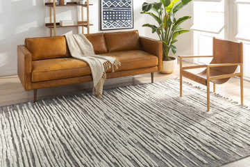 Bright living room with a brown leather sofa and the charcoal and cream Mahaffey Area Rug. Roomscene-Rectangle
