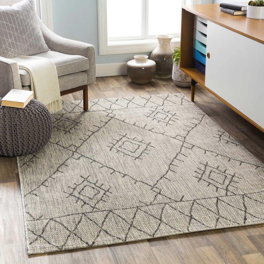 Living room scene with gray armchair and Marwood Nordic Performance Rug in black, charcoal, taupe, and white. Roomscene-Rectangle
