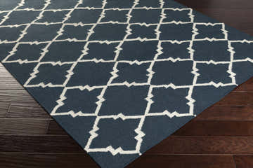 Close up of the hand woven Maryneal Area Carpet. Cream geometric pattern on dark blue 100% wool rug. Corner