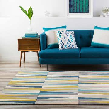 Living room scene with a blue sofa and the Mathiston Geometric Triangles Wool Rug in beige, blue, and mustard. Roomscene-Rectangle