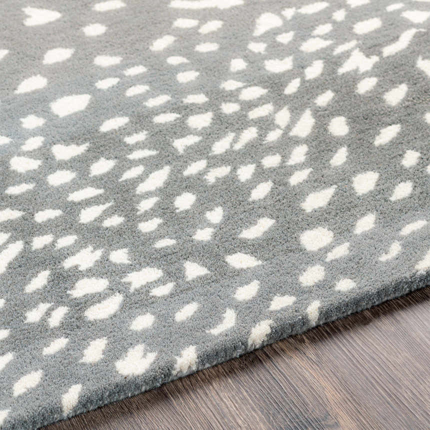 Close-up of the Athena Gray Giraffe Print Wool Rug. Cream spots on a light gray, hand-tufted wool rug. Contemporary animal style. Texture