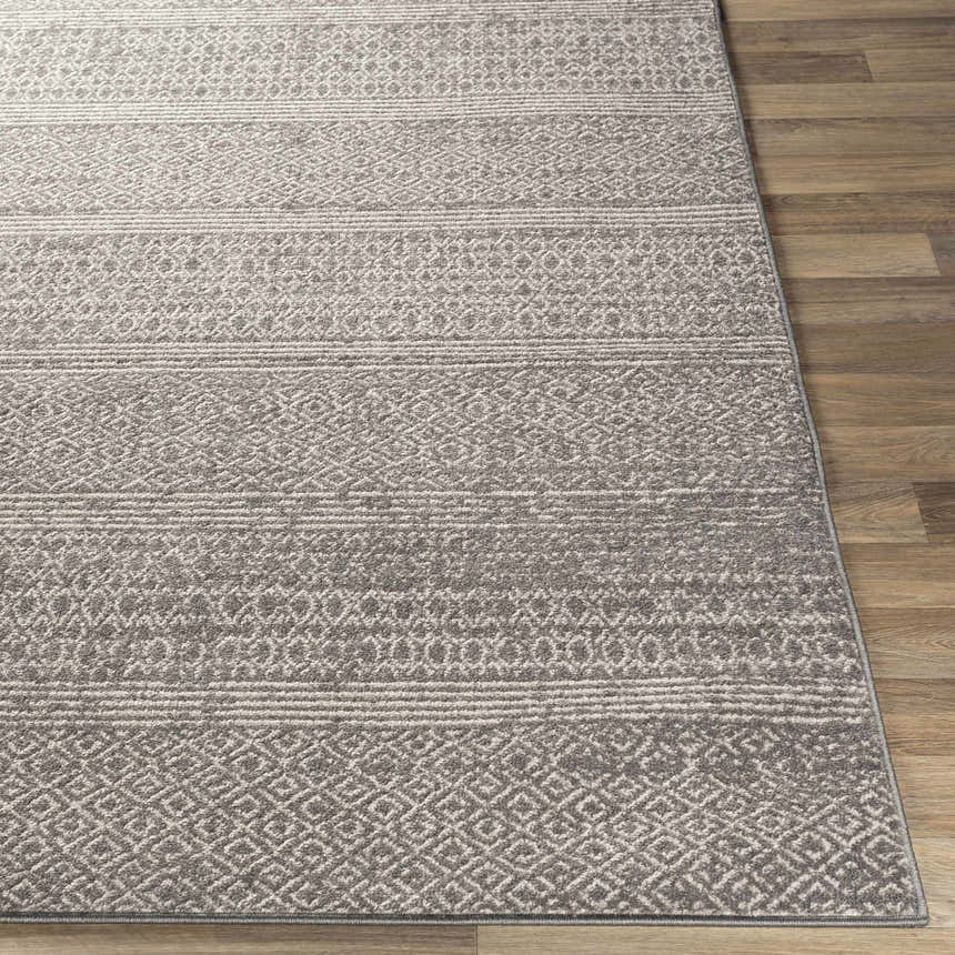 Close-up of the Mckinney Area Rug. Charcoal, light beige, and gray geometric pattern on a machine-woven polypropylene rug. Front