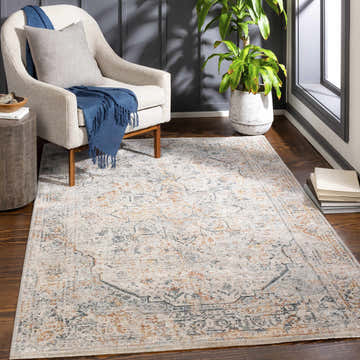 Living room scene with a McKinlay Luxe Rug in brick red, cream, and gray, styled with a chair, side table, and plant. Roomscene-Rectangle