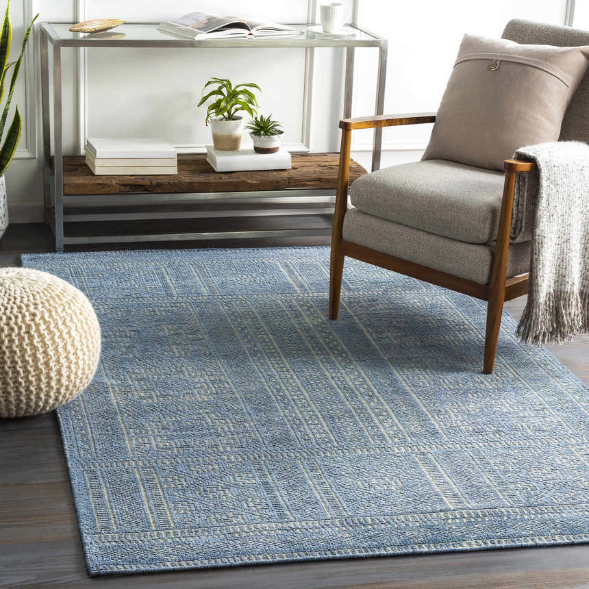 Living room scene with a blue and oatmeal Meigs Premium Viscose & Wool Rug, gray chair, wood console table, and neutral accents. Roomscene-Rectangle